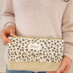 Pochette modèle Lila tenue dans les mains en sherpa beige et coton léopard.