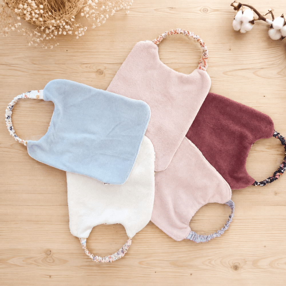 Dos des bavoirs de maternelle en tissus éponge aubergine, rose clair, blanc et bleu.